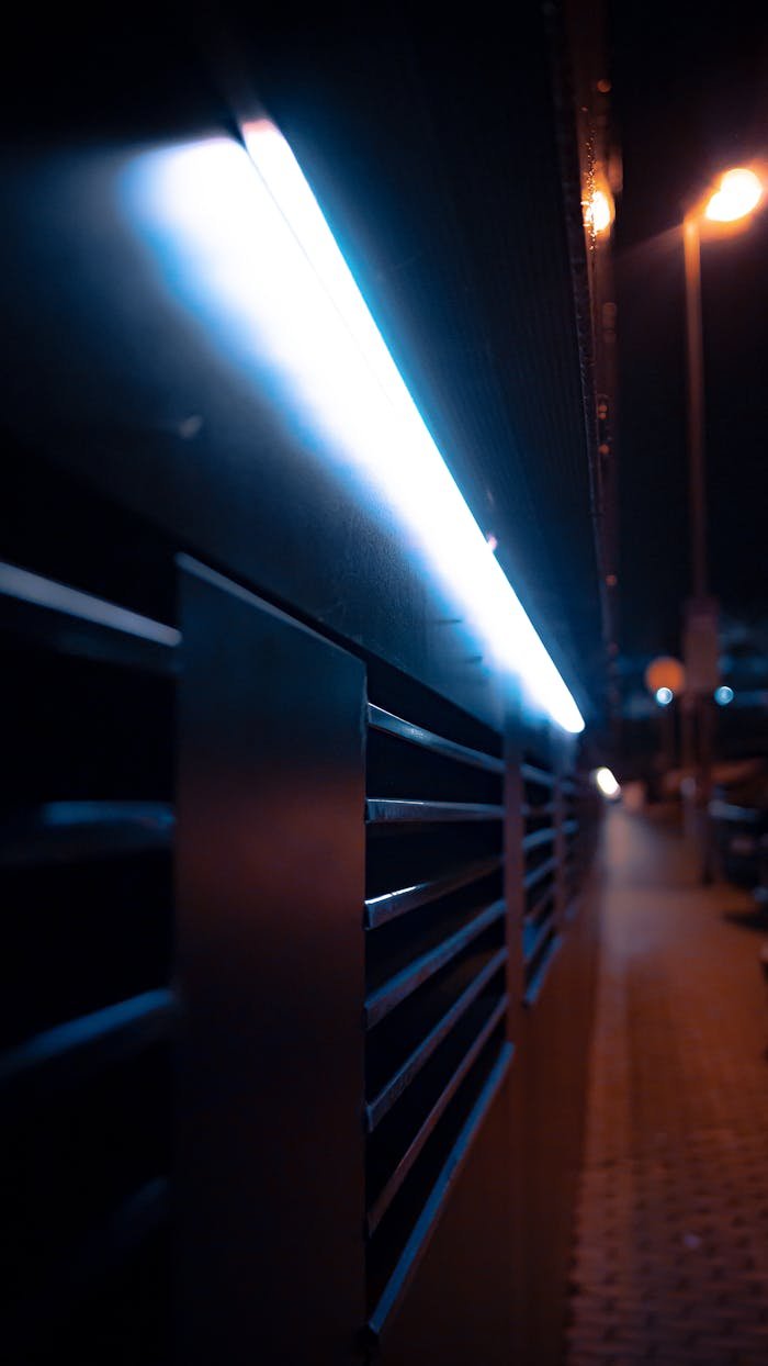 A close-up of a modern urban facade with blue LED lighting on a city street at night.